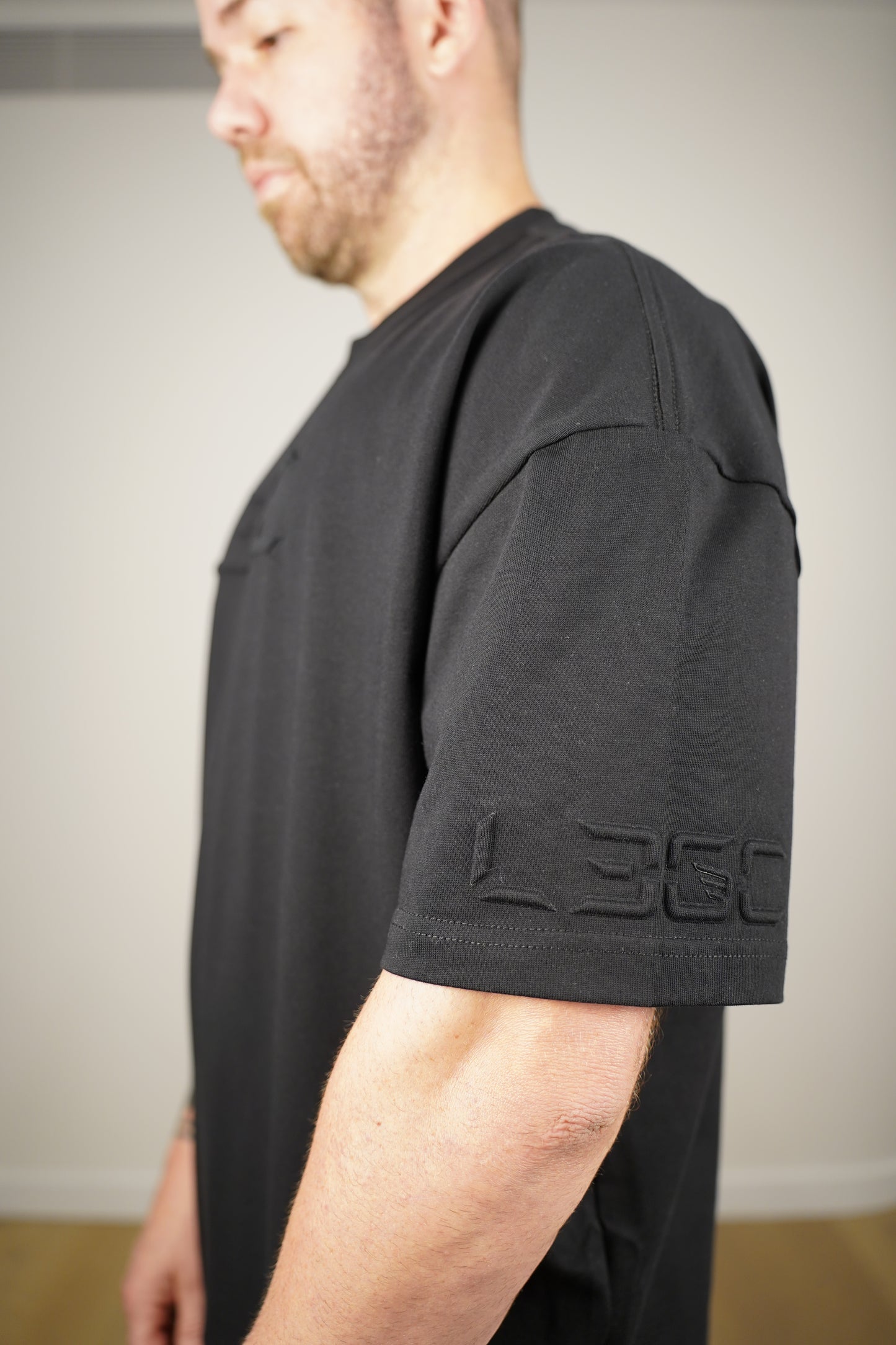 Person wearing black tee with a brand logo.