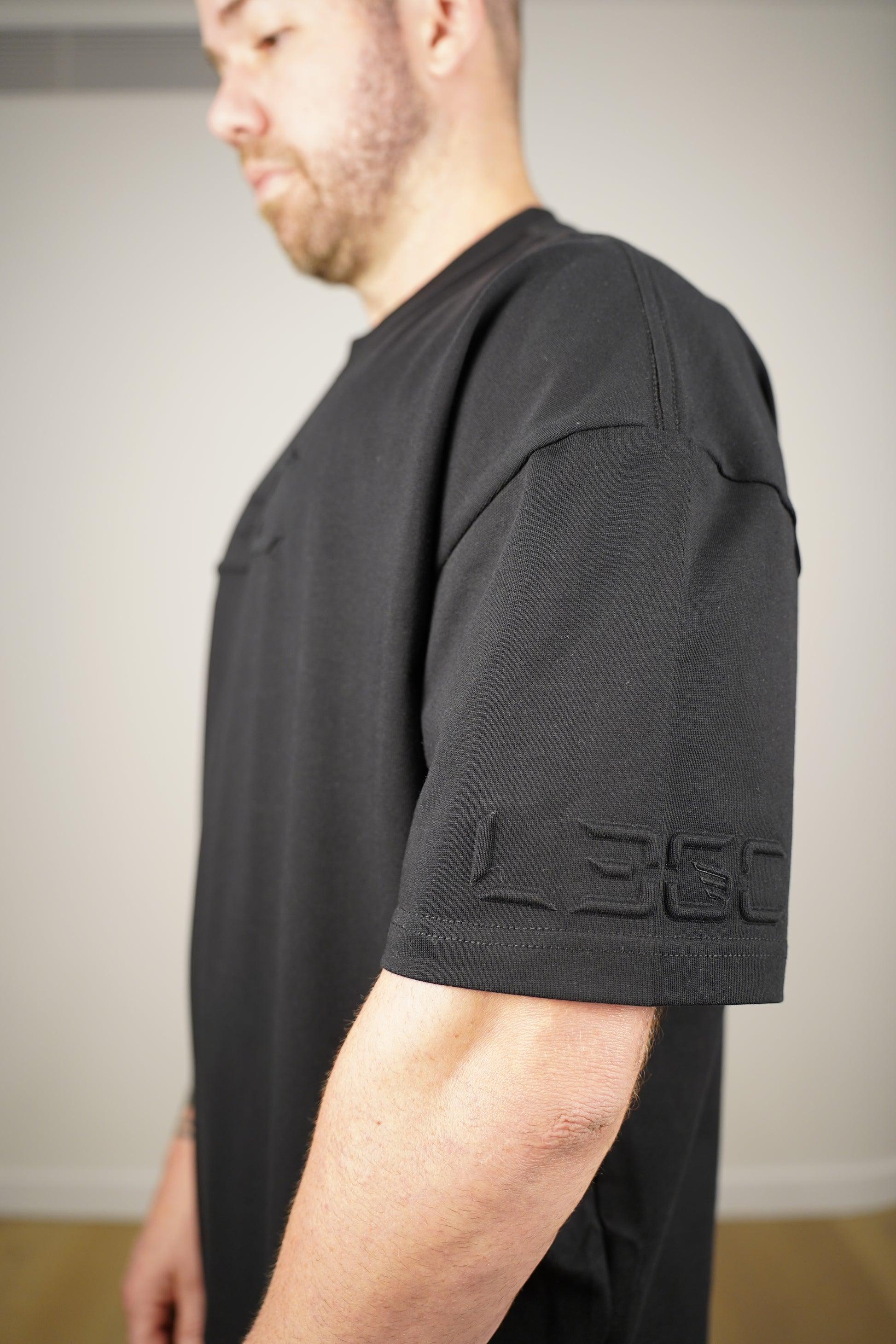Person wearing black tee with a brand logo.
