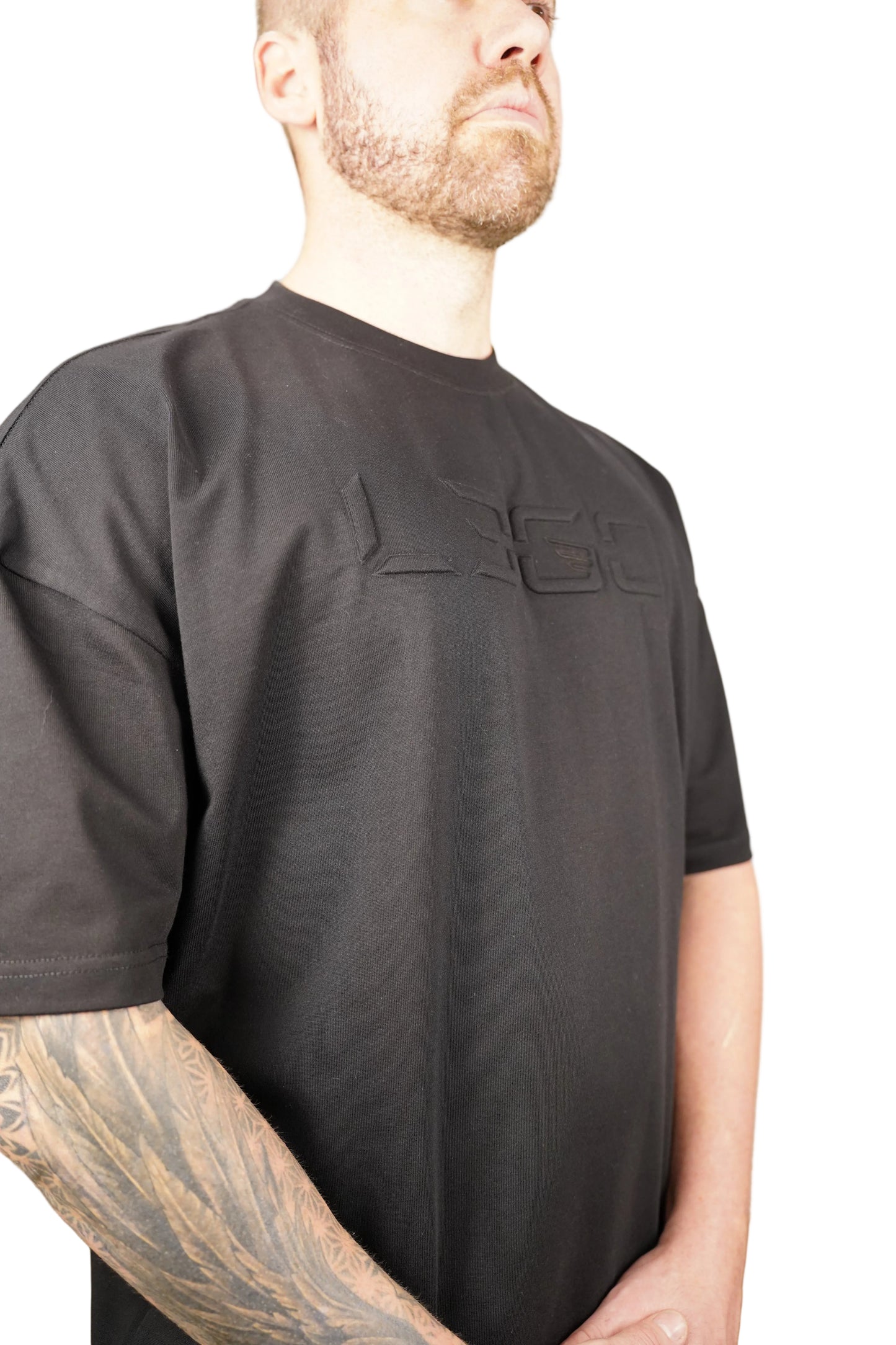 Person wearing a black suit with a logo on a neutral background