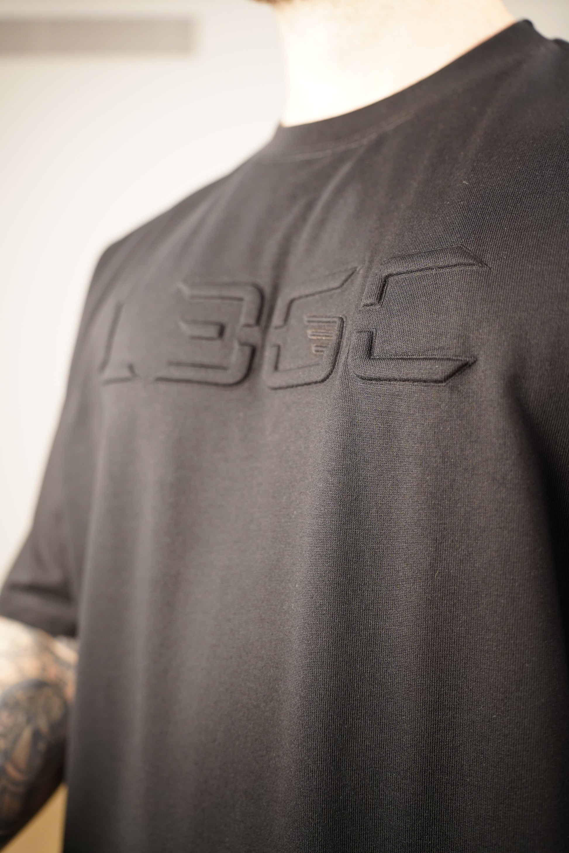 Black shirt with a logo on a person wearing it.
