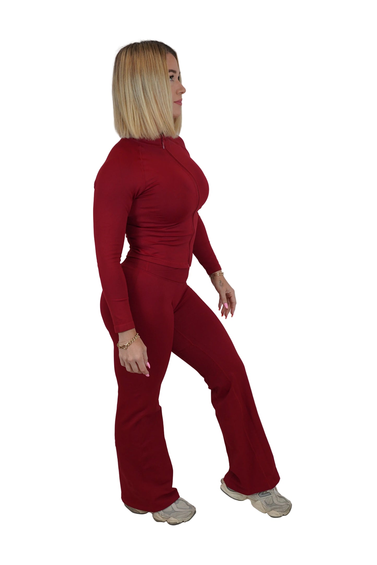 A woman modeling a matching red long-sleeve mock-neck top and wide-leg pants set, standing against a white studio backdrop.
