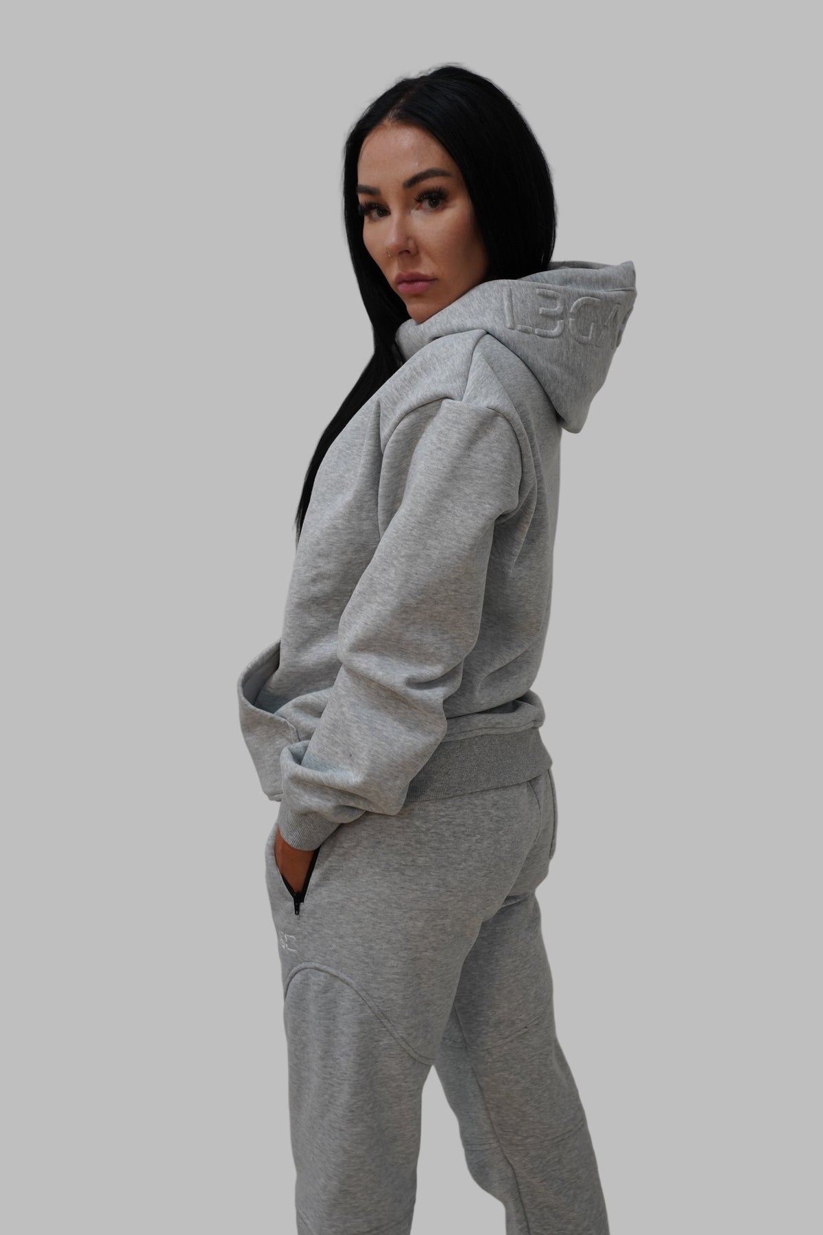 Person wearing a gray hoodie and pants against a plain background