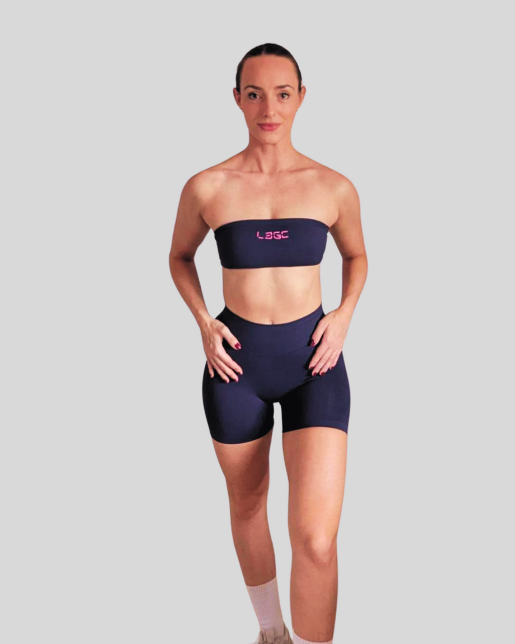 A female model wearing navy blue bandeau-style sports bra with a logo on the front.