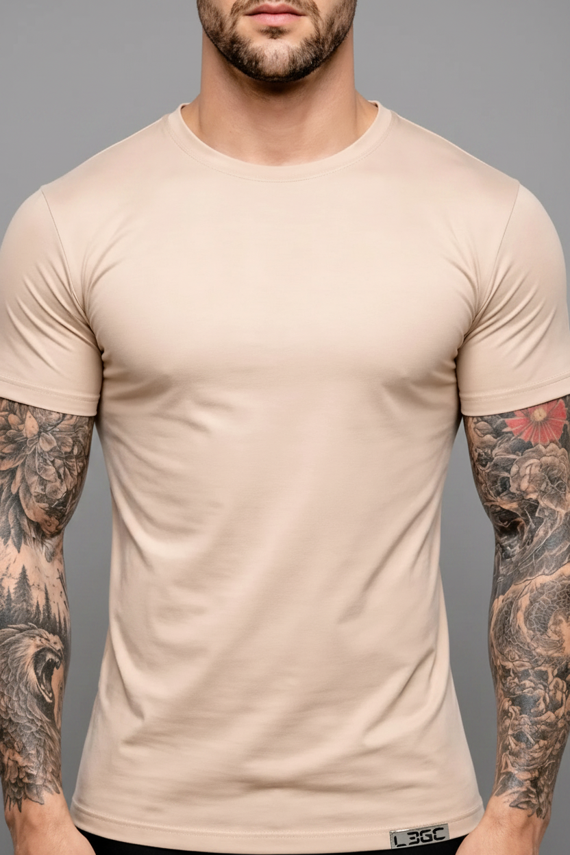 Man wearing a beige t-shirt with tattoos on arms against a white background
