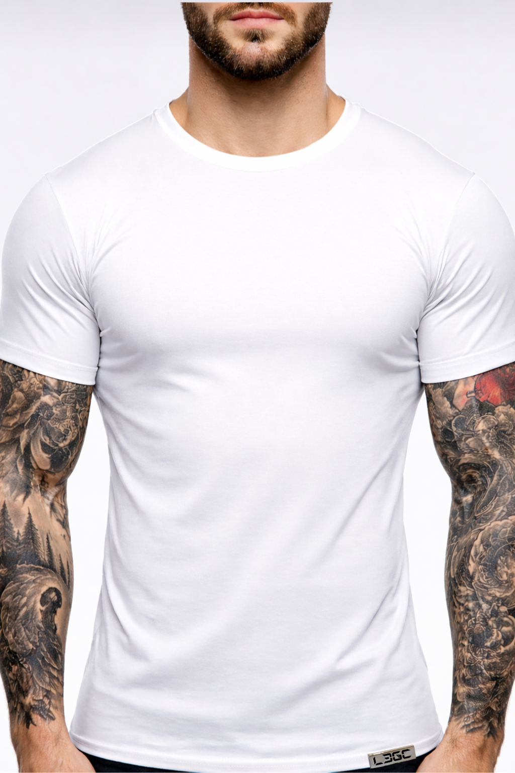 Man wearing a plain white t-shirt with tattoos on arms against a white background