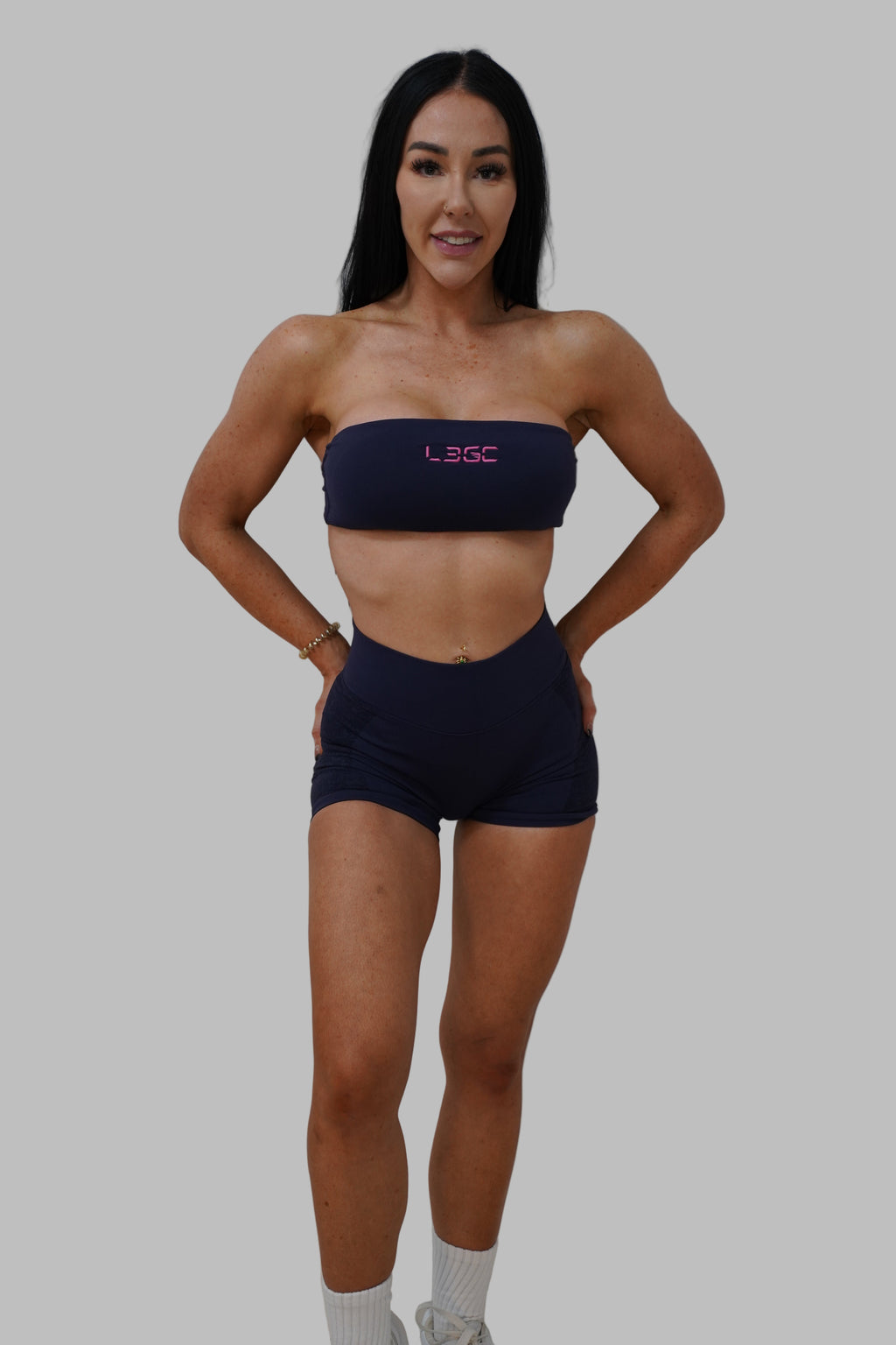 Person wearing a navy blue sports bra and shorts on a plain background
