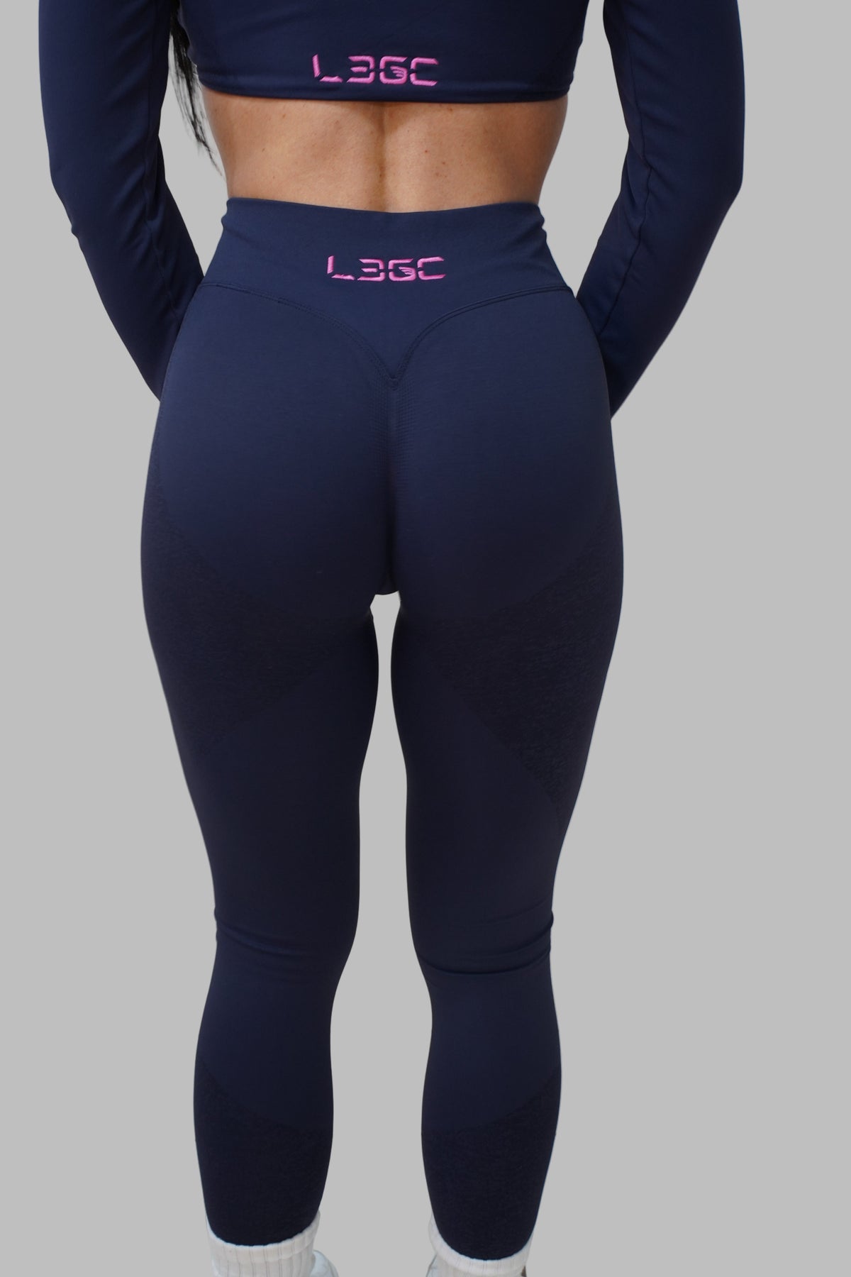 woman wearing navy leggings with 'Legc' branding in hot pink