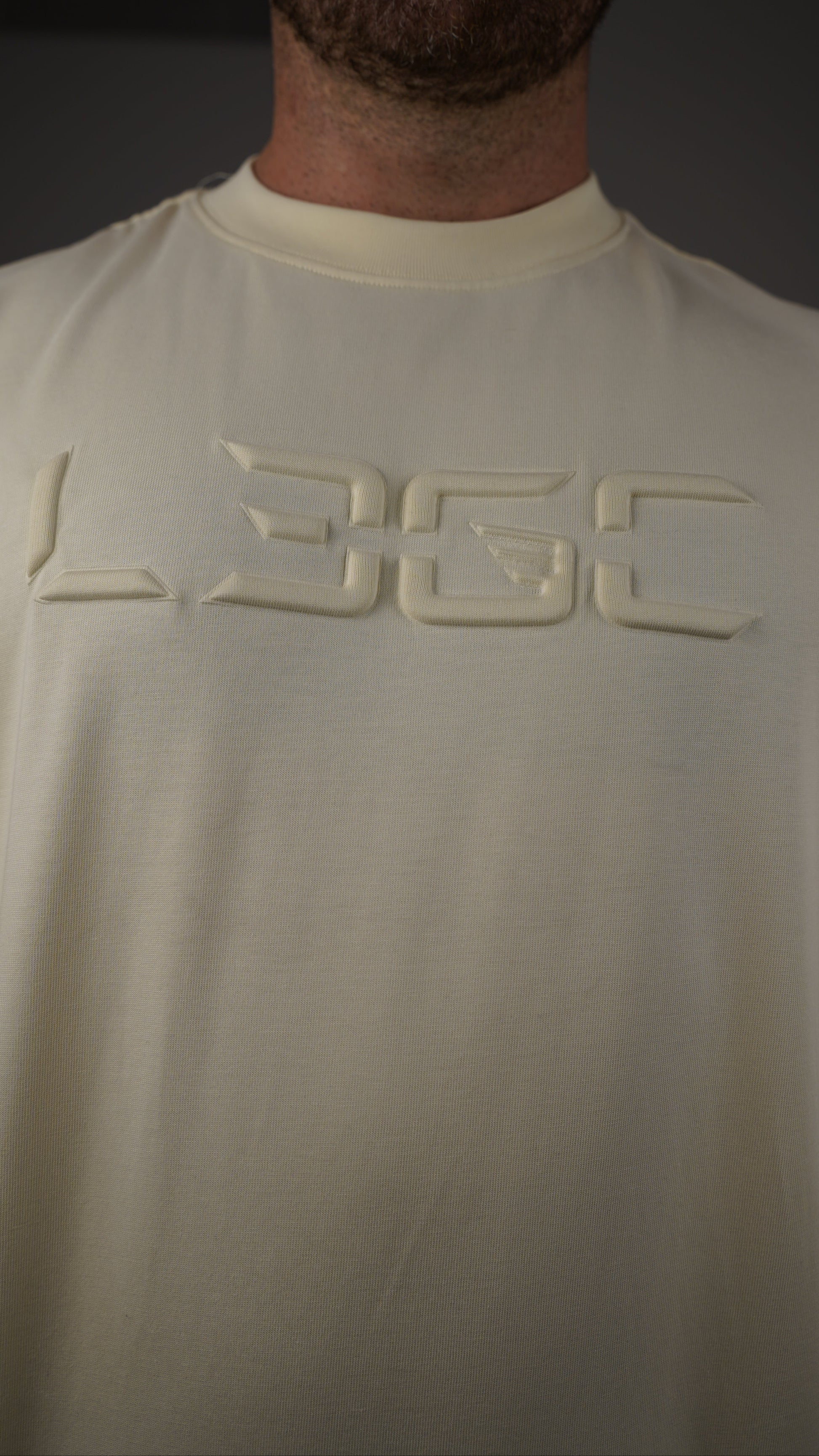 Close-up of a person wearing a white sleeveless shirt with a logo on the chest.