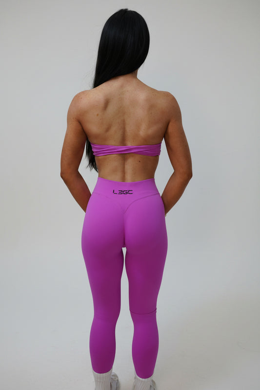 woman wearing bright pink leggings and a sports bra.