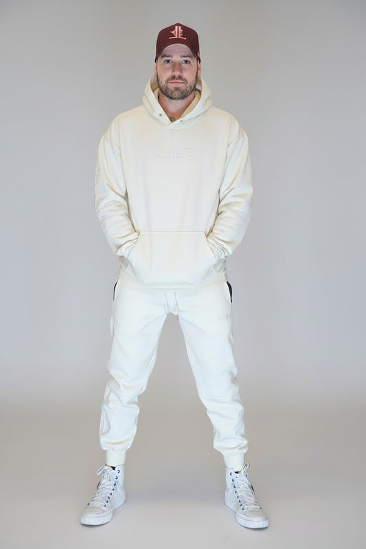 Person wearing a white tracksuit and red cap standing in front of a metallic shutter.