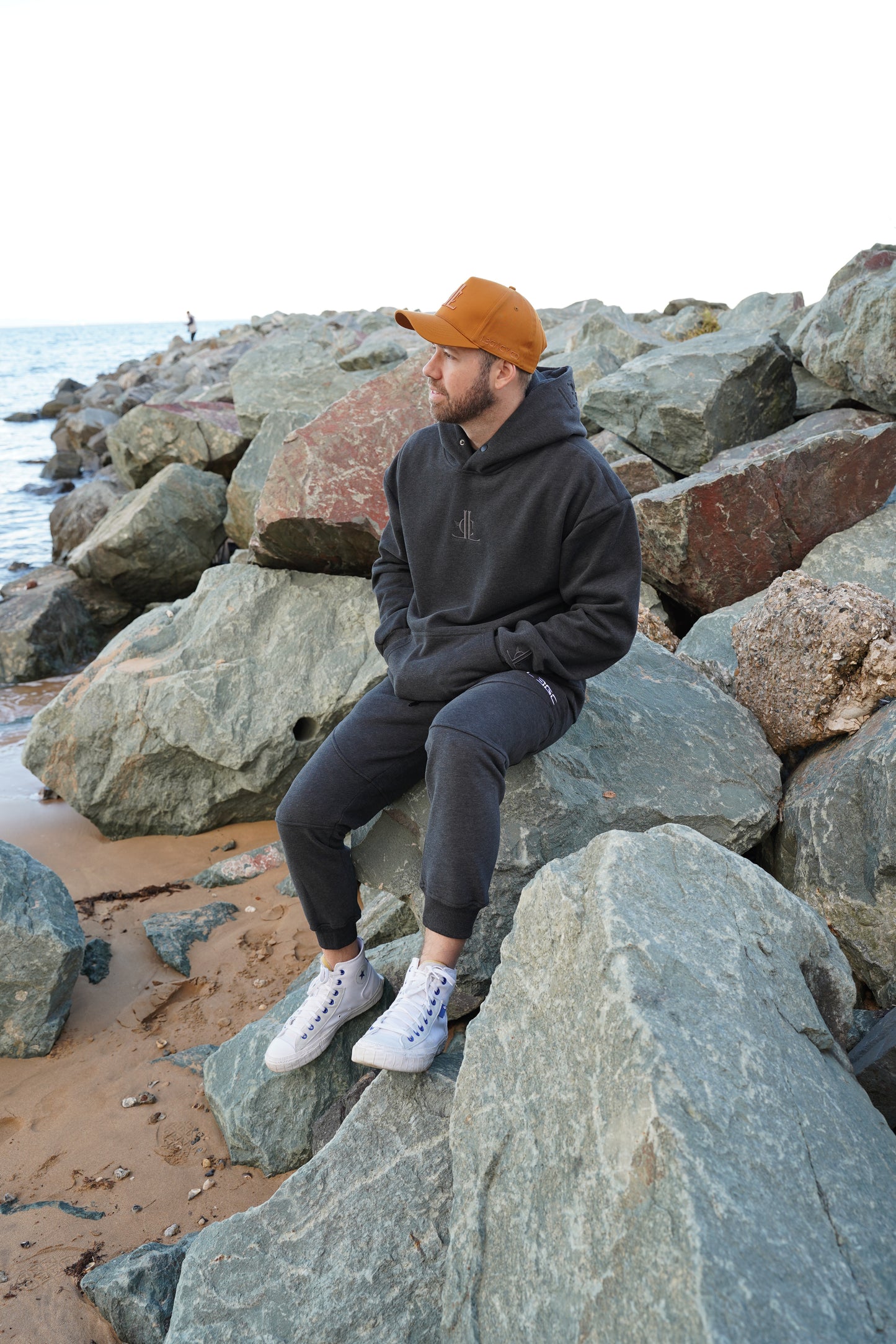 Person climbing a rocky wall wearing a black jacket and orange beanie.