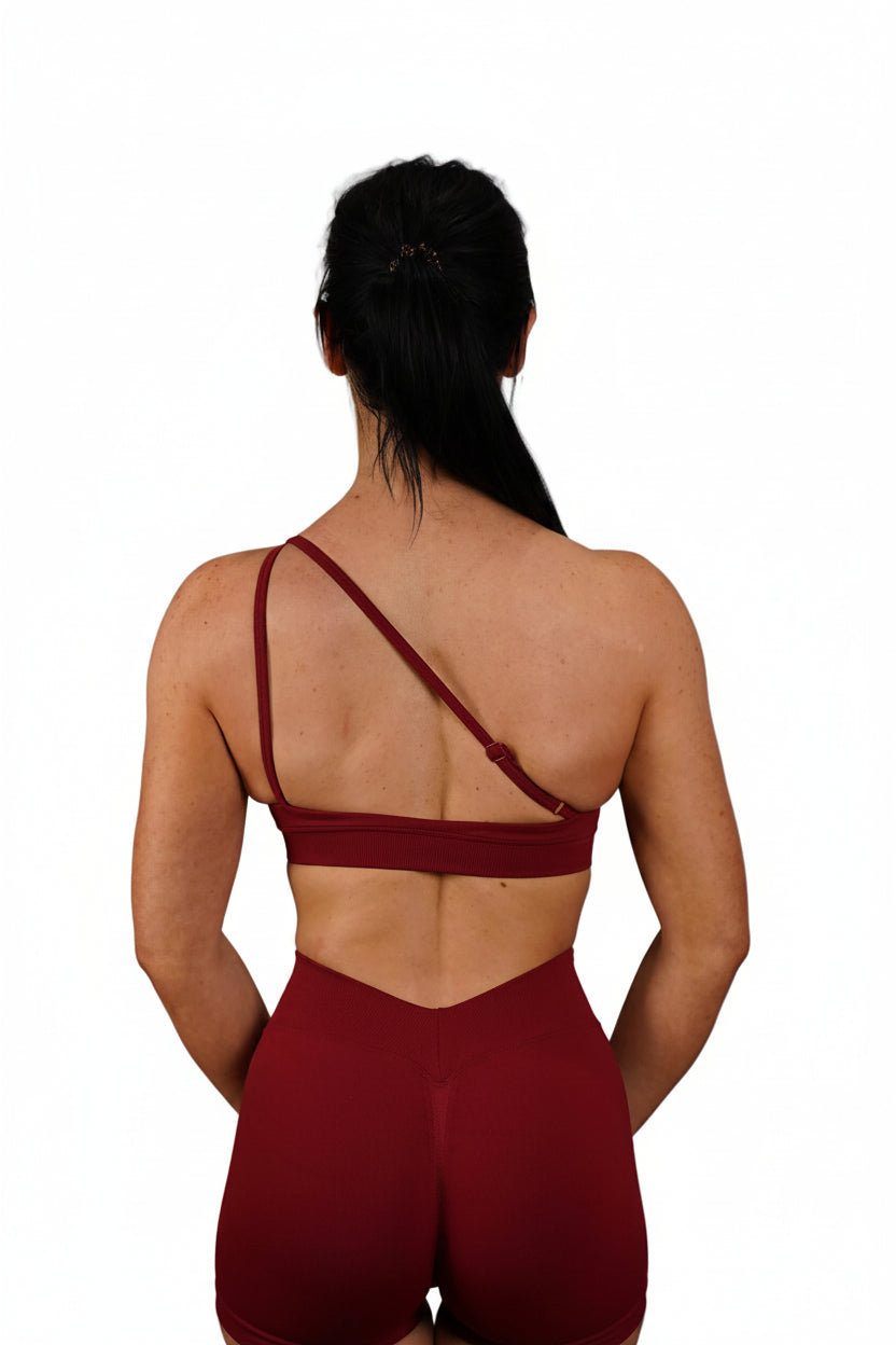 Person wearing a burgundy sports bra and shorts on a white background