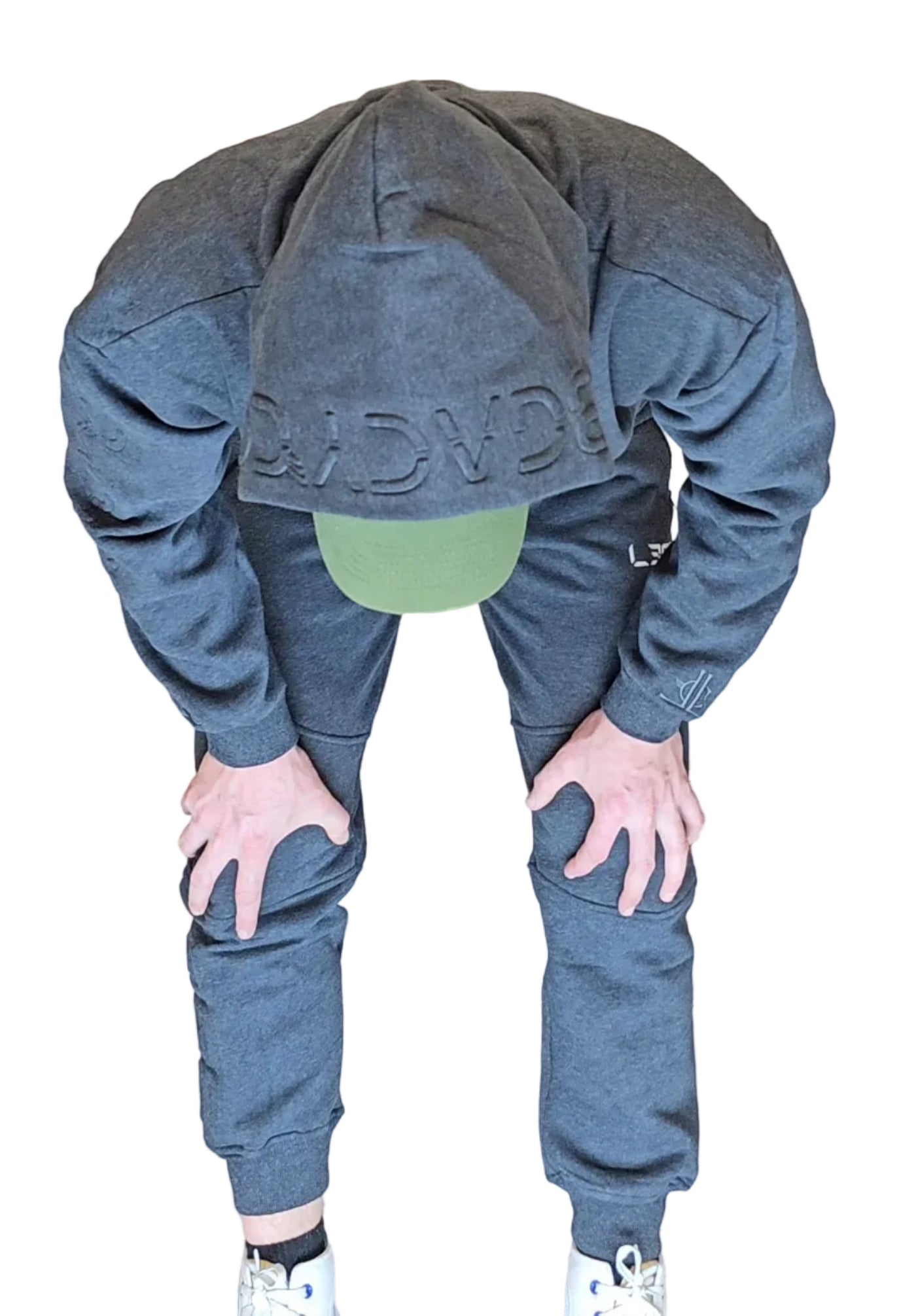 Person wearing a gray hoodie and pants with a green beanie in front of a metallic shutter.