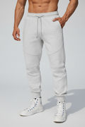 Person wearing light gray jogger pants and white sneakers on a rooftop.