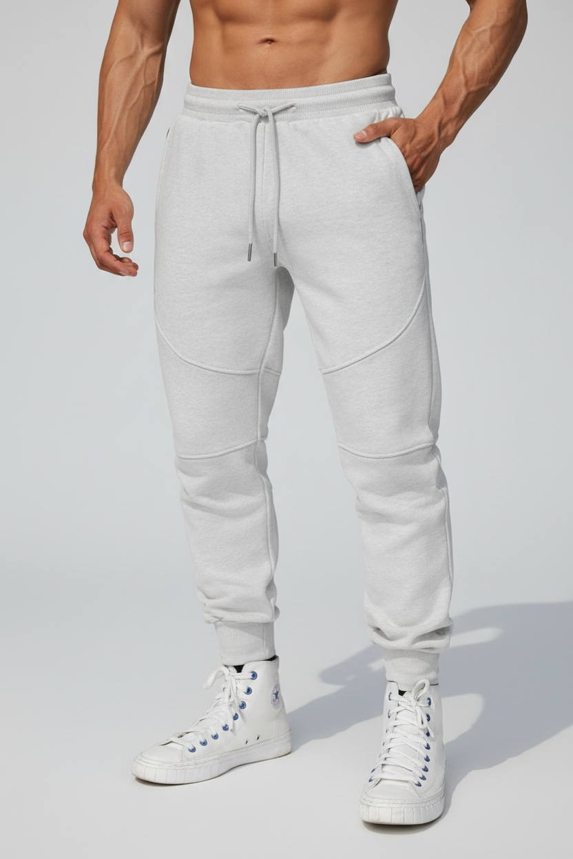Person wearing light gray jogger pants and white sneakers on a rooftop.