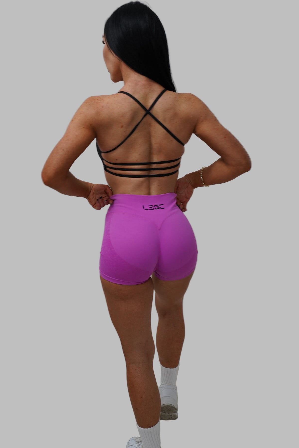 woman wearing a black strappy top and pink shorts.